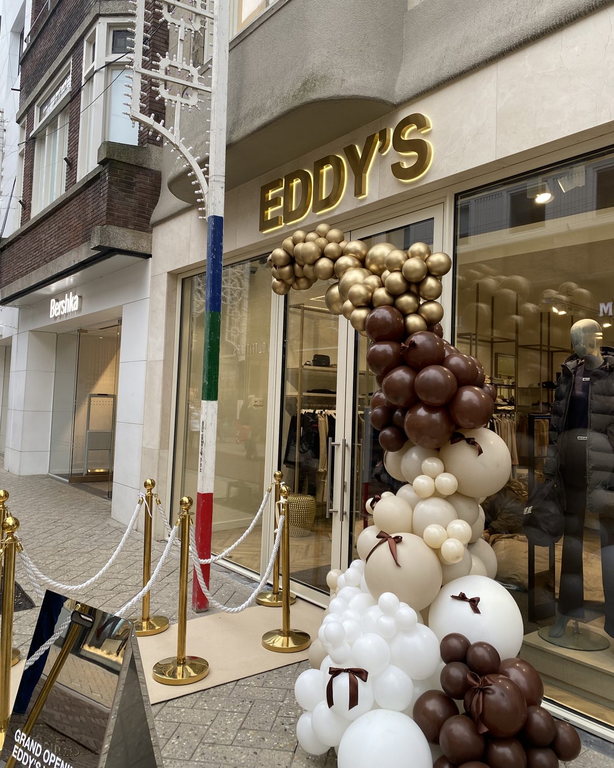 The Eddy's shopfront on opening day: gold EDDY'S sign, a balloon arch in gold, chocolate and cream, and a Grand opening stand